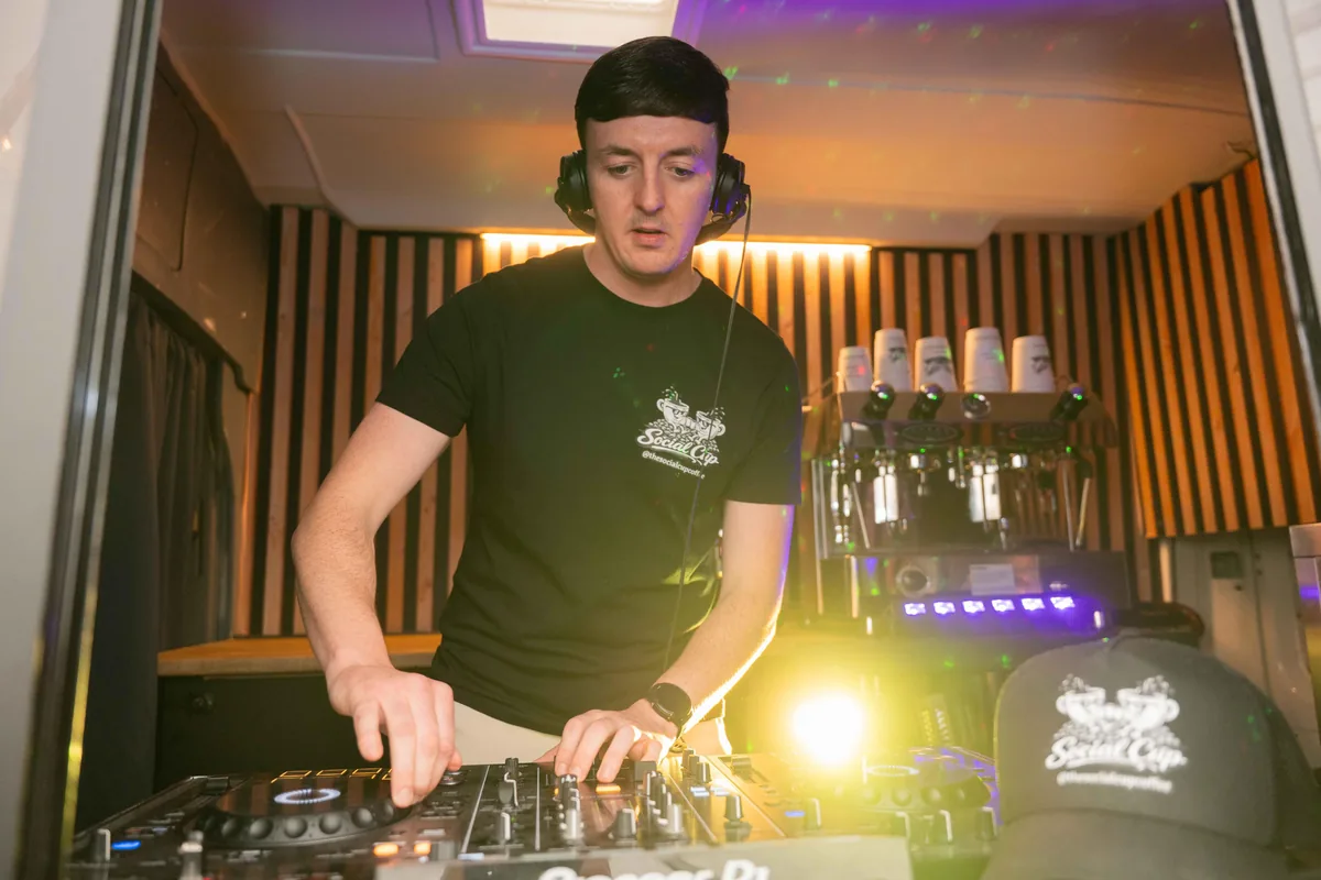 Connor Doyle DJing from inside the Social Cup coffee van, decks set up where the coffee bar serves